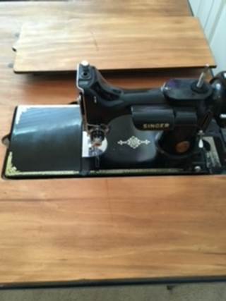 A black sewing machine on a wooden surface

Description automatically generated