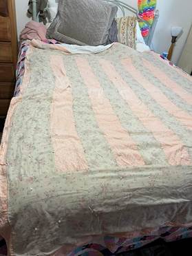 A bed with a pink and grey striped blanket

Description automatically generated